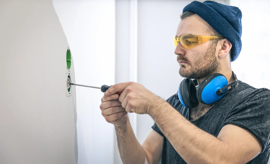 Electrician or HVAC technician working on an electrical switchboard or outlet installation for an HVAC system